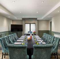Elegant hotel meeting room with plush blue chairs and a long table, set for a business event.