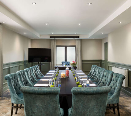 Elegant hotel meeting room with plush blue chairs and a long table, set for a business event.