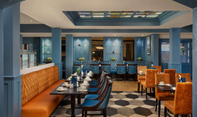 Hotel dining area with blue and orange decor, tables set for a family meal.