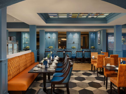 Hotel dining area with blue and orange decor, tables set for a family meal.