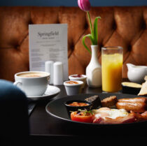 Family enjoying hearty breakfast at Springfield Hotel with fresh juice and coffee.