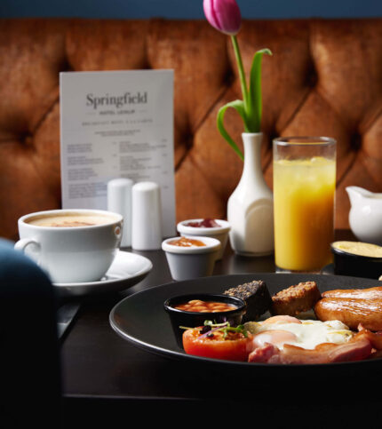 Family enjoying hearty breakfast at Springfield Hotel with fresh juice and coffee.