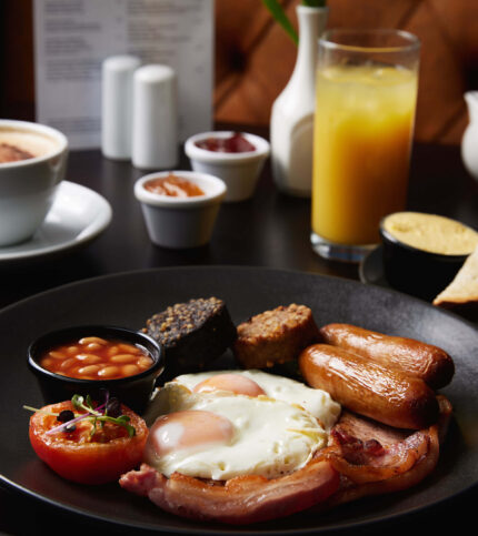 Hearty English breakfast with eggs, sausages, and beans in a cosy restaurant setting.