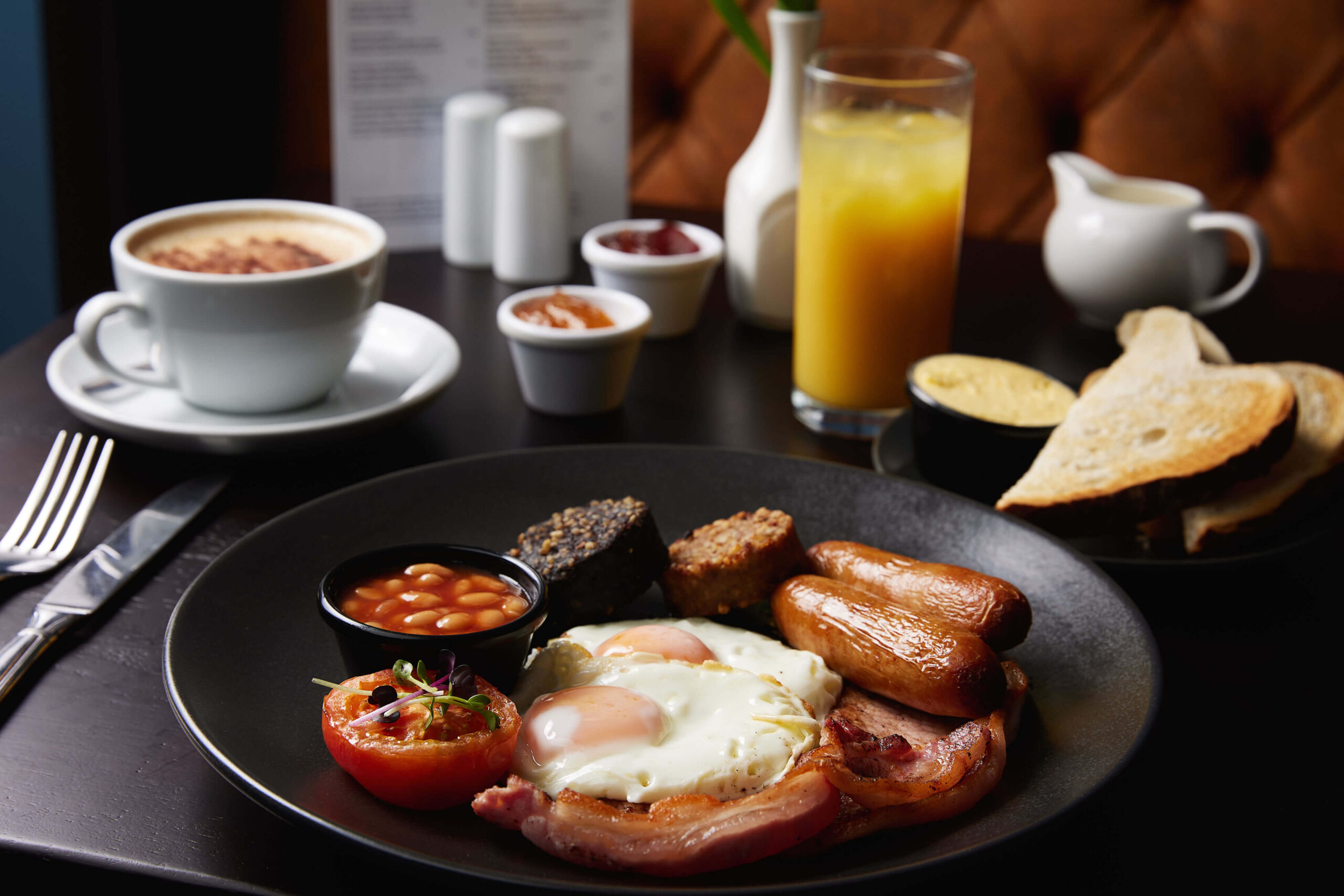 Hearty English breakfast with eggs, sausages, and beans in a cosy restaurant setting.