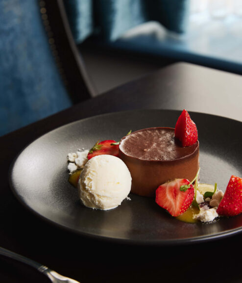 Elegant dessert with chocolate tart and ice cream in hotel dining setting.