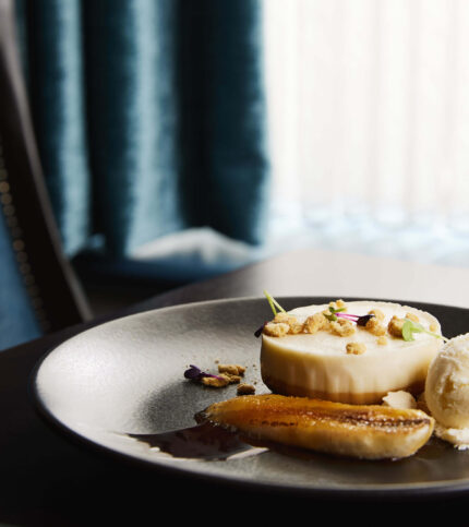 Elegant dessert setting with pudding, ice cream, and champagne in a refined dining area.