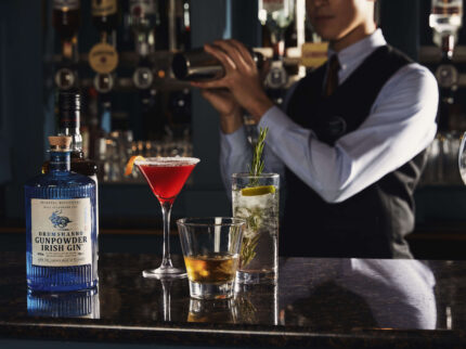 Bartender mixing drinks at elegant hotel bar featuring assorted cocktails.