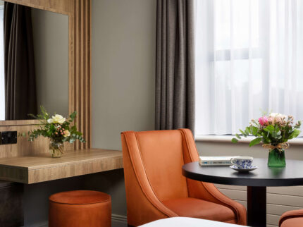 Cosy hotel room with a table and flowers, warm lighting, and modern furnishings.