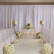 Elegant hotel wedding setup with floral decor and candlelit aisle.