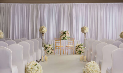 Elegant hotel wedding setup with floral decor and candlelit aisle.