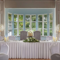 Elegant wedding table setup with flowers in a bright, serene room with large windows.