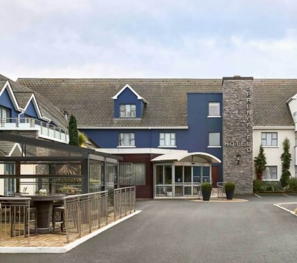 Family enjoys Springfield Hotel entrance, blue facade with welcoming outdoor seating area.