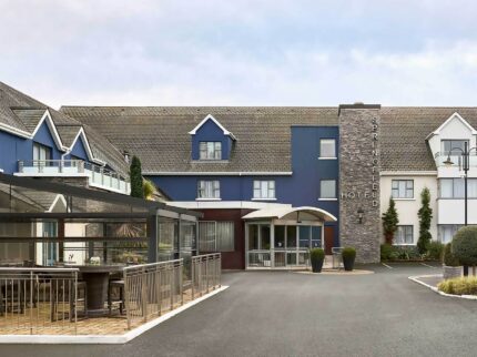 Family enjoys Springfield Hotel entrance, blue facade with welcoming outdoor seating area.