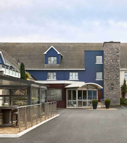 Family enjoys Springfield Hotel entrance, blue facade with welcoming outdoor seating area.