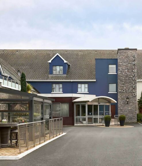 Family enjoys Springfield Hotel entrance, blue facade with welcoming outdoor seating area.