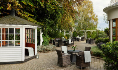 Serene hotel garden with tables and a small gazebo, ideal for family gatherings.