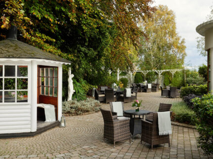 Serene hotel garden with tables and a small gazebo, ideal for family gatherings.