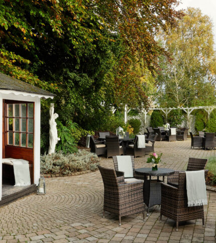 Serene hotel garden with tables and a small gazebo, ideal for family gatherings.