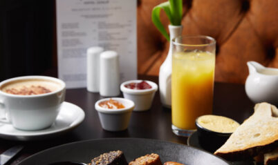 A warm, inviting breakfast setting at Springfield Hotel with a full English breakfast, drinks, and a menu.