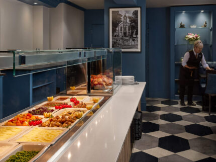 Elegant hotel buffet with assorted dishes and staff preparing tables in a welcoming setting.