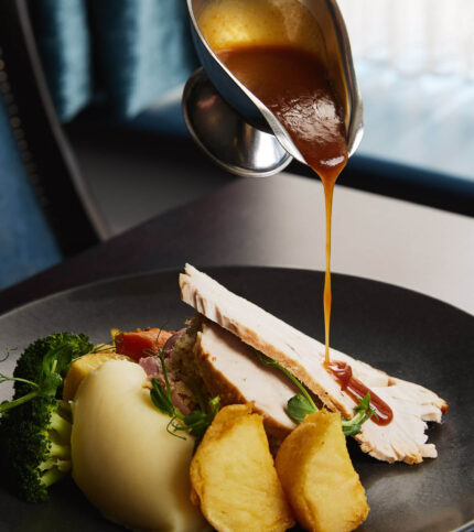 Gourmet roast dinner with gravy in a cosy hotel restaurant.