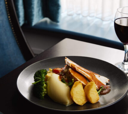 Elegant hotel dining with gourmet meal and wine near window