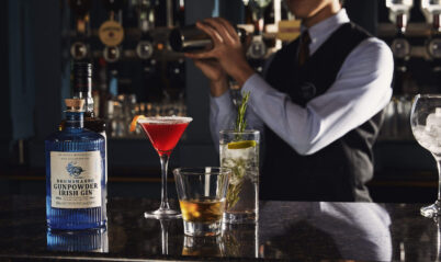 A hotel bartender mixes drinks for guests at a cosy, elegant bar featuring cocktails.