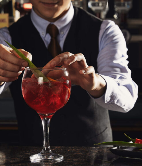 Bartender crafting a vibrant cocktail at Springfield Hotel bar.