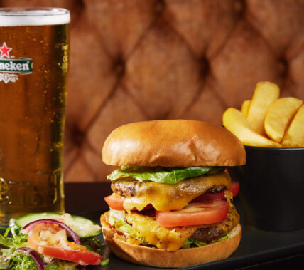 Juicy burger and chips with a refreshing pint on a cosy restaurant table.