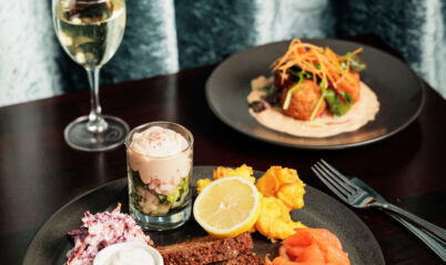 Elegant dining setup with gourmet dishes and a glass of white wine at Springfield Hotel.