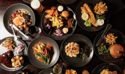 A family enjoying diverse plates of gourmet dishes including burgers, fries, and salads at Springfield Hotel.