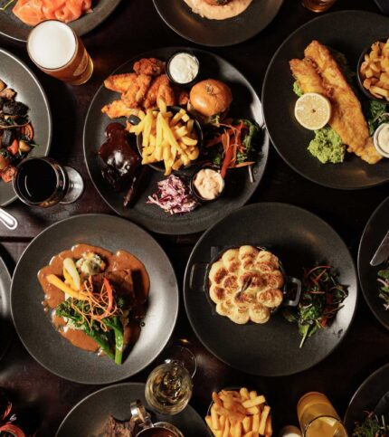 A family enjoying diverse plates of gourmet dishes including burgers, fries, and salads at Springfield Hotel.