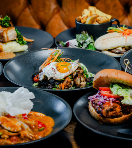 A table set with various gourmet meals, including salads, sandwiches, and rice dishes.