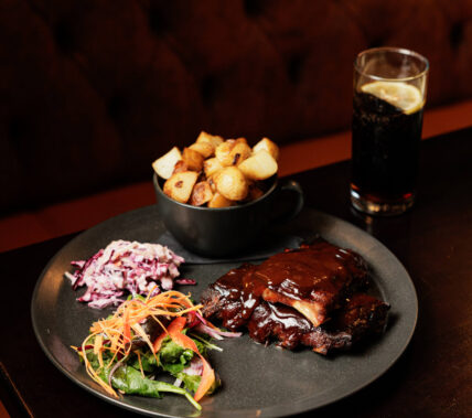 Delicious barbecue meal with ribs, slaw, potatoes, and drink at Springfield Hotel restaurant.