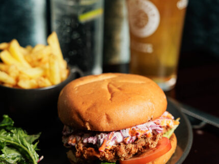 A delicious burger with coleslaw, chips, salad, and drinks at Springfield Hotel.
