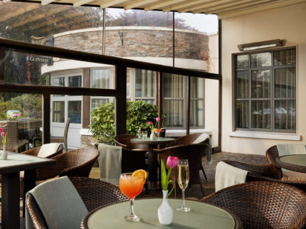 Relaxing hotel terrace with drinks, wicker chairs, and fresh tulips on tables.