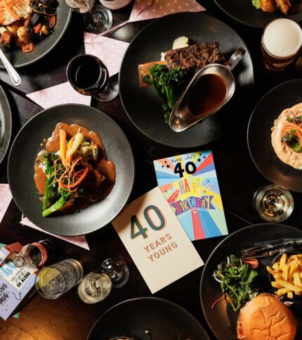 A warm family meal with "40 Years Young" birthday card surrounded by delicious dishes and drinks.