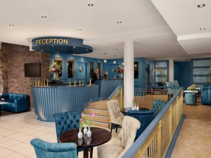 A welcoming hotel reception area with a family checking in, featuring elegant blue decor.