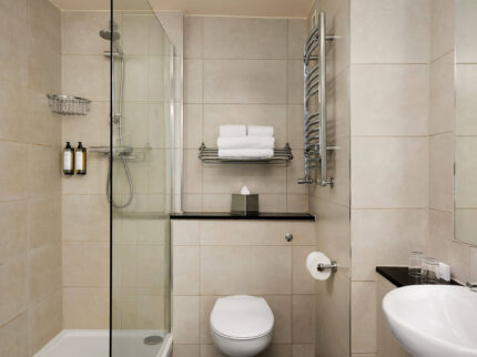 Modern hotel bathroom with a glass shower, fluffy towels, and luxury toiletries.