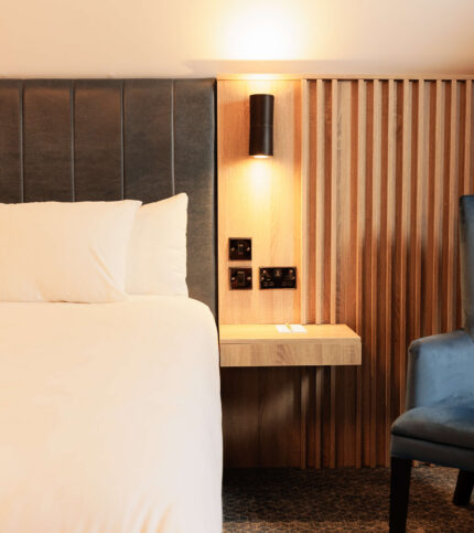 Cosy hotel room with plush bed, soft lighting, and modern wooden decor.
