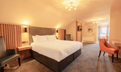 Spacious hotel room with cosy lighting and a king-size bed.