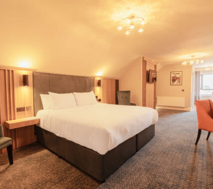 Spacious hotel room with cosy lighting and a king-size bed.