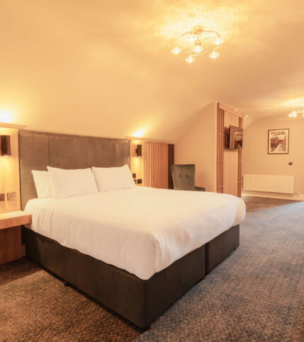 Spacious hotel room with cosy lighting and a king-size bed.