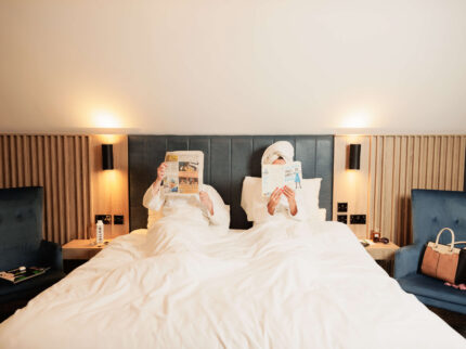 A relaxing couple in robes, reading in bed at Springfield Hotel, enjoying a cosy stay.