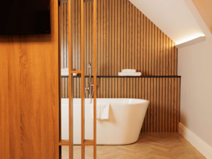 Cozy hotel room with inviting bathtub and warm wooden accents.