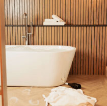 Luxurious hotel bathroom with tub, wooden panelling, and relaxing amenities.