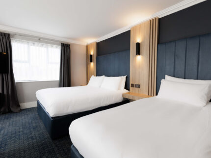 Welcoming hotel room with two double beds and modern decor.