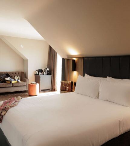 Elegant hotel room with a cosy double bed and seating area, ideal for a relaxing stay.