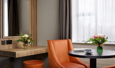 Stylish hotel room with a cosy seating area and floral arrangements on a small round table.