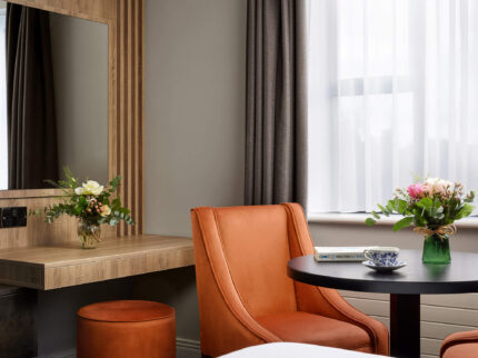 Stylish hotel room with a cosy seating area and floral arrangements on a small round table.